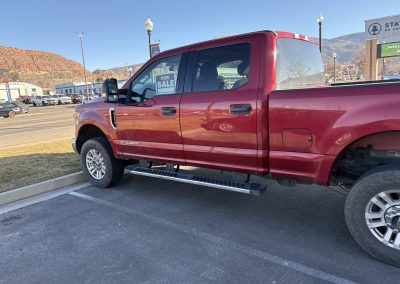 Red pickup truck parked with a for‑sale sign in the window.