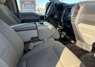 Interior of a truck with front seats, console, and a for‑sale sign.