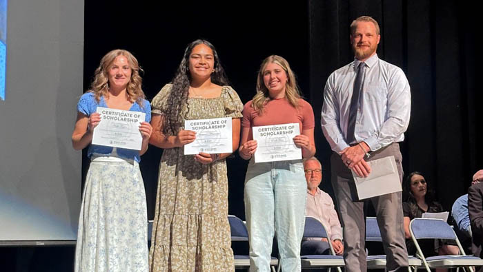 high school students holding scholarship certificates