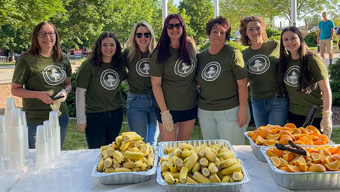 people posing for a picture in front of a table of bananas.