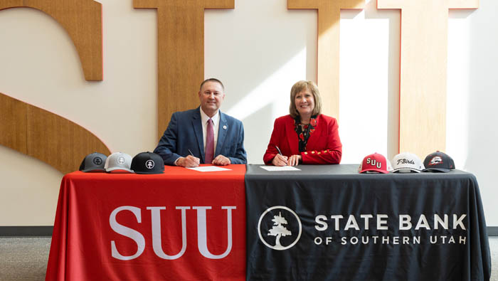 SBSU CEO and SUU President posing at a table signing a contract.